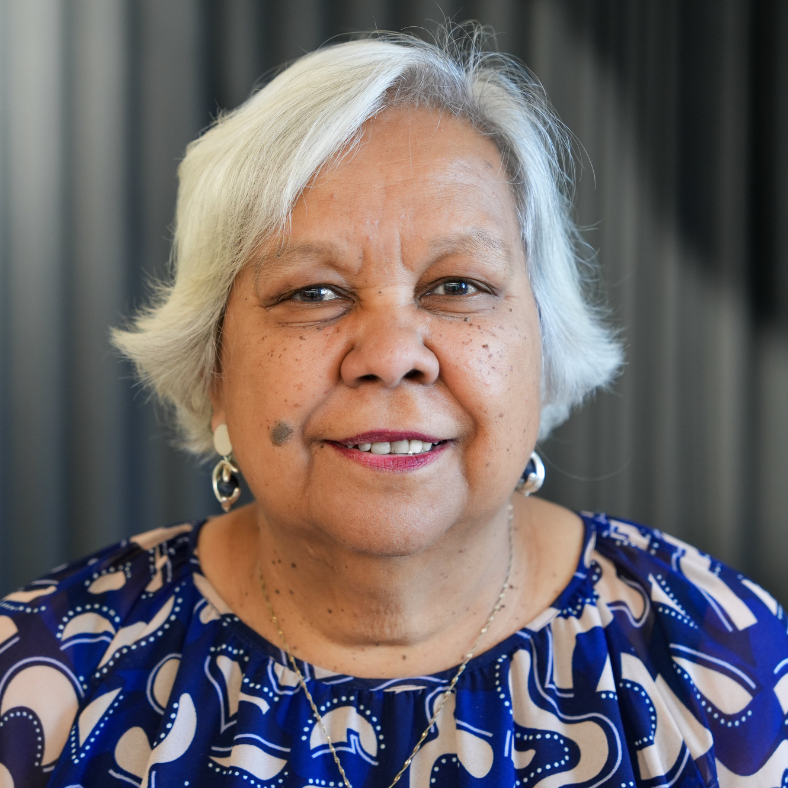 Older woman with short white hair smiling against softly blurred indoor background